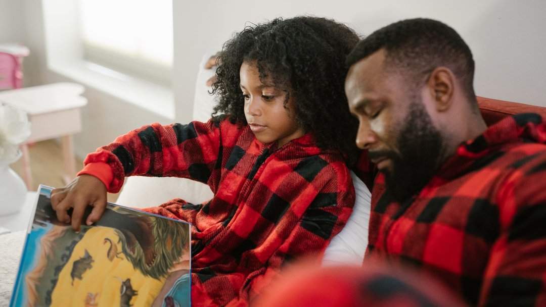 图 / Pexels · RDNE Stock project A father and daughter enjoying a bonding moment while reading a book together in matching pajamas.