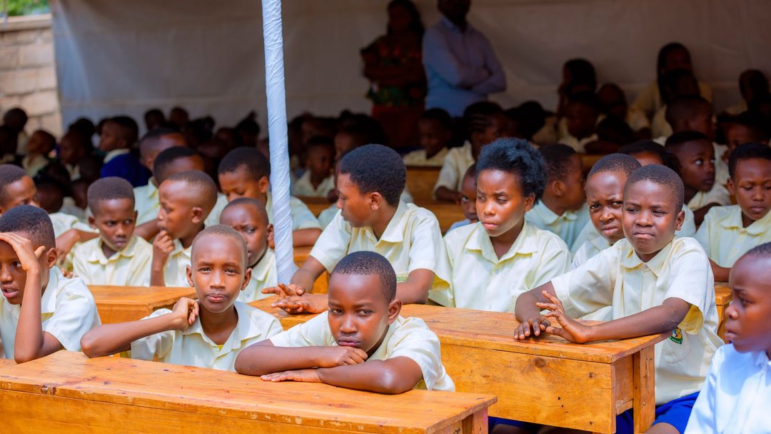 A group of African schoolchildren engaged in learning at an outdoor class setting.